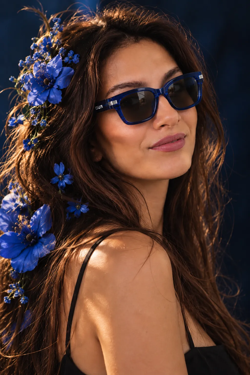A woman in cobalt Ova sunglasses with blue flowers in her hair