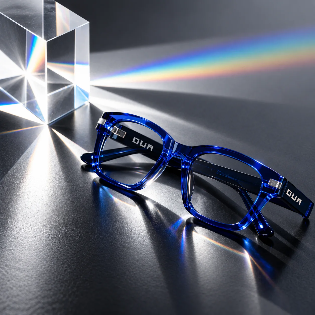 Cobalt Ova glasses beside a glass prism casting a rainbow